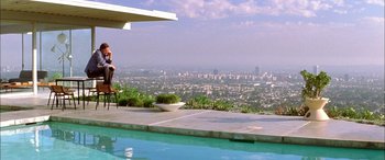 Movie still from “Where the Truth Lies” (2005), directed by Atom Egoyan – A man sitting on a chair next to a swimming pool; Extreme Wide shot, High angle