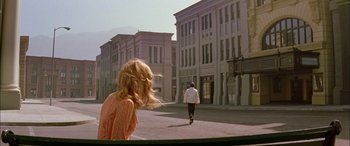 Movie still from “Where the Truth Lies” (2005), directed by Atom Egoyan – Two people walking down a street near a tall building; Wide shot, Over the shoulder angle