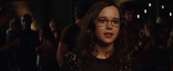 Movie still from “Whip It” (2009), directed by Drew Barrymore – A woman with glasses is standing in a room; Close Up shot, Over the shoulder angle