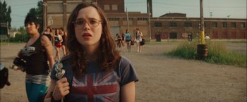 Movie still from “Whip It” (2009), directed by Drew Barrymore – A woman with glasses is standing in the street; Close Up shot, Over the shoulder angle
