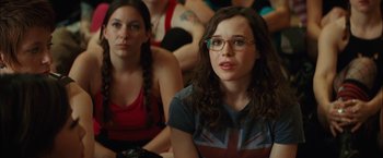 Movie still from “Whip It” (2009), directed by Drew Barrymore – Two women sitting in front of each other in front of a group of people; Close Up shot, Over the shoulder angle