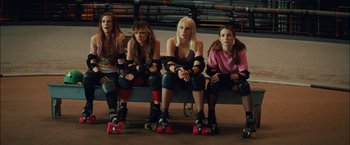 Movie still from “Whip It” (2009), directed by Drew Barrymore – A group of women sitting next to each other on roller skates; Medium shot, Low angle