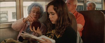 Movie still from “Whip It” (2009), directed by Drew Barrymore – A young girl is reading a book on a train; Medium shot, Over the shoulder angle