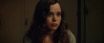 Movie still from “Whip It” (2009), directed by Drew Barrymore – A woman with long brown curly hair stares into the camera; Close Up shot, Over the shoulder angle