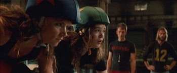 Movie still from “Whip It” (2009), directed by Drew Barrymore – A group of young people riding bikes in a room; Close Up shot, Over the shoulder angle