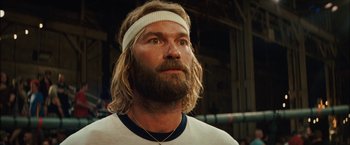 Movie still from “Whip It” (2009), directed by Drew Barrymore – A man with long hair and a beard wearing a headband; Close Up shot, Low angle