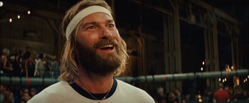 Movie still from “Whip It” (2009), directed by Drew Barrymore – A man with long hair and a beard wearing a headband; Close Up shot, Low angle