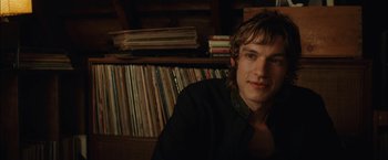 Movie still from “Whip It” (2009), directed by Drew Barrymore – A man sitting in front of a bunch of records; Close Up shot, Over the shoulder angle