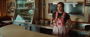 Movie still from “Whip It” (2009), directed by Drew Barrymore – A woman standing in front of a counter in a kitchen; Medium shot, Over the shoulder angle