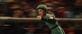 Movie still from “Whip It” (2009), directed by Drew Barrymore – A girl in a green uniform and a yellow helmet is holding onto a rail; Medium shot, Low angle
