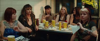 Movie still from “Whip It” (2009), directed by Drew Barrymore – A group of people sitting at a table with plates of food on it; Medium shot, Over the shoulder angle