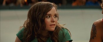 Movie still from “Whip It” (2009), directed by Drew Barrymore – A woman with long hair sitting down looking to her left; Close Up shot, Over the shoulder angle