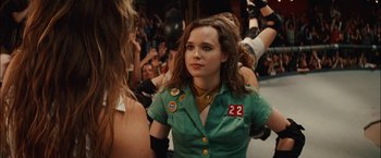 Movie still from “Whip It” (2009), directed by Drew Barrymore – A woman in a green shirt is standing in front of a group of people; Close Up shot, Over the shoulder angle