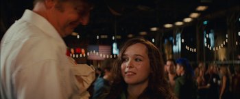 Movie still from “Whip It” (2009), directed by Drew Barrymore – A young woman smiles at the camera while a man looks at her; Close Up shot, Over the shoulder angle