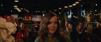 Movie still from “Whip It” (2009), directed by Drew Barrymore – A woman with long brown hair smiles for the camera; Close Up shot, Over the shoulder angle