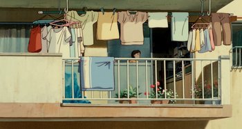 Movie still from “Whisper of the Heart” (1995), directed by Yoshifumi Kondô – A person standing on a balcony next to a bunch of clothes; Wide shot, High angle