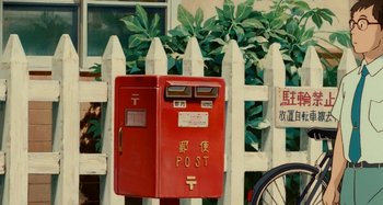 Movie still from “Whisper of the Heart” (1995), directed by Yoshifumi Kondô – A red post box sitting in front of a white picket fence; Extreme Close Up shot, Low angle