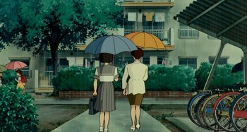 Movie still from “Whisper of the Heart” (1995), directed by Yoshifumi Kondô – Two women walking down a sidewalk holding umbrellas; Wide shot, Low angle