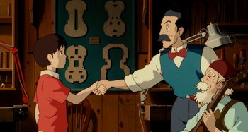Movie still from “Whisper of the Heart” (1995), directed by Yoshifumi Kondô – A man and a boy shaking hands in front of a wall of musical instruments; Medium shot, Over the shoulder angle