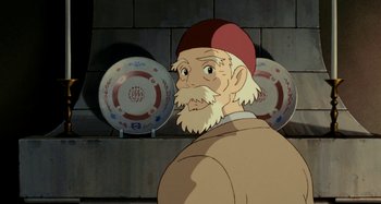 Movie still from “Whisper of the Heart” (1995), directed by Yoshifumi Kondô – An old man with a beard and a red hat is looking at the camera; Close Up shot, Low angle