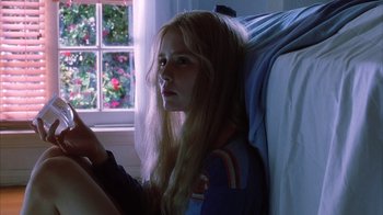Movie still from “White Oleander” (2002), directed by Peter Kosminsky – A girl sitting on a bed looking at the camera; Close Up shot, Low angle