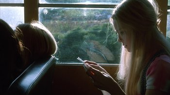 Movie still from “White Oleander” (2002), directed by Peter Kosminsky – A woman sitting in front of a window holding a cigarette in her hand; Close Up shot, Over the shoulder angle
