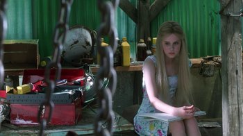 Movie still from “White Oleander” (2002), directed by Peter Kosminsky – A woman sitting on the ground in front of a chain link fence; Medium shot, Over the shoulder angle