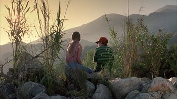 Movie still from “White Oleander” (2002), directed by Peter Kosminsky – Two children sitting on rocks in a field; Wide shot, High angle