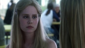 Movie still from “White Oleander” (2002), directed by Peter Kosminsky – A young woman with long blonde hair looking at the camera; Close Up shot, Over the shoulder angle