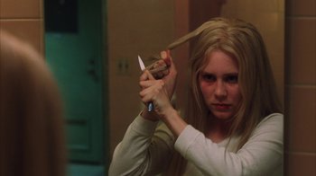 Movie still from “White Oleander” (2002), directed by Peter Kosminsky – A woman cutting her hair with a pair of shears; Close Up shot, High angle
