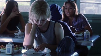 Movie still from “White Oleander” (2002), directed by Peter Kosminsky – A woman sitting at a table looking at a piece of paper; Medium shot, Over the shoulder angle