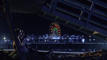 Movie still from “White Oleander” (2002), directed by Peter Kosminsky – A ferris wheel is lit up at night in the dark; Wide shot, Over the shoulder angle