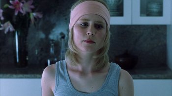 Movie still from “White Oleander” (2002), directed by Peter Kosminsky – A woman wearing a pink head band in a room; Close Up shot, Low angle