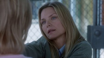 Movie still from “White Oleander” (2002), directed by Peter Kosminsky – A person sitting in front of a fence; Close Up shot, Over the shoulder angle