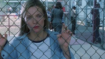 Movie still from “White Oleander” (2002), directed by Peter Kosminsky – A woman smoking a cigarette behind a chain link fence; Close Up shot, Over the shoulder angle