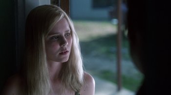 Movie still from “White Oleander” (2002), directed by Peter Kosminsky – A woman with long blonde hair looking out a window; Close Up shot, Over the shoulder angle
