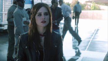 Movie still from “White Oleander” (2002), directed by Peter Kosminsky – A woman in a leather jacket standing in front of a group of people; Medium shot, Over the shoulder angle