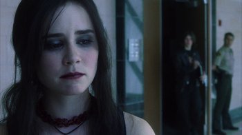 Movie still from “White Oleander” (2002), directed by Peter Kosminsky – A young woman wearing a red necklace looks at the camera while a man stands behind her; Close Up shot, Over the shoulder angle