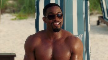 Movie still from “Why Did I Get Married Too?” (2010), directed by Tyler Perry – A shirtless man sitting on top of a beach chair; Medium shot, Over the shoulder angle