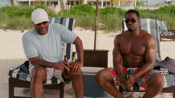 Movie still from “Why Did I Get Married Too?” (2010), directed by Tyler Perry – A couple of men sitting next to each other on a beach; Medium shot, Over the shoulder angle