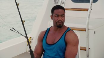 Movie still from “Why Did I Get Married Too?” (2010), directed by Tyler Perry – A man sitting on the side of a boat holding a fishing pole; Medium shot, Over the shoulder angle