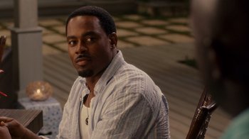 Movie still from “Why Did I Get Married Too?” (2010), directed by Tyler Perry – A man sitting on the ground wearing a white shirt; Close Up shot, Over the shoulder angle