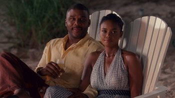 Movie still from “Why Did I Get Married Too?” (2010), directed by Tyler Perry – A man and a woman sitting next to each other holding wine glasses; Medium shot, Over the shoulder angle