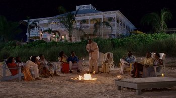 Movie still from “Why Did I Get Married Too?” (2010), directed by Tyler Perry – A group of people sitting around a fire on the beach; Extreme Wide shot, High angle