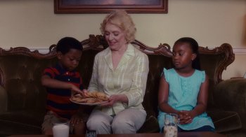 Movie still from “Why Did I Get Married Too?” (2010), directed by Tyler Perry – An older woman sitting on a couch holding a plate of food; Medium shot, Over the shoulder angle