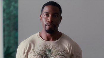 Movie still from “Why Did I Get Married Too?” (2010), directed by Tyler Perry – A man with a beard wearing a t - shirt with a tree on it; Close Up shot, Low angle