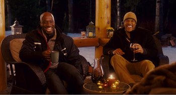 Movie still from “Why Did I Get Married?” (2007), directed by Tyler Perry – Two men are sitting on a couch and drinking wine; Medium shot, Over the shoulder angle