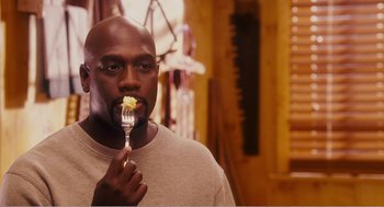 Movie still from “Why Did I Get Married?” (2007), directed by Tyler Perry – A man holding a fork with a piece of food in it; Close Up shot, Overhead angle