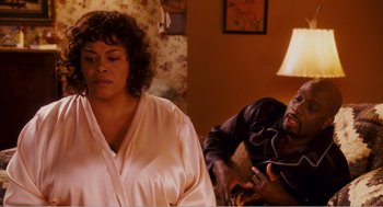Movie still from “Why Did I Get Married?” (2007), directed by Tyler Perry – A woman and a man sitting in a living room next to each other; Medium shot, Over the shoulder angle