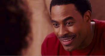 Movie still from “Why Did I Get Married?” (2007), directed by Tyler Perry – A person with a smile on his face; Close Up shot, Over the shoulder angle